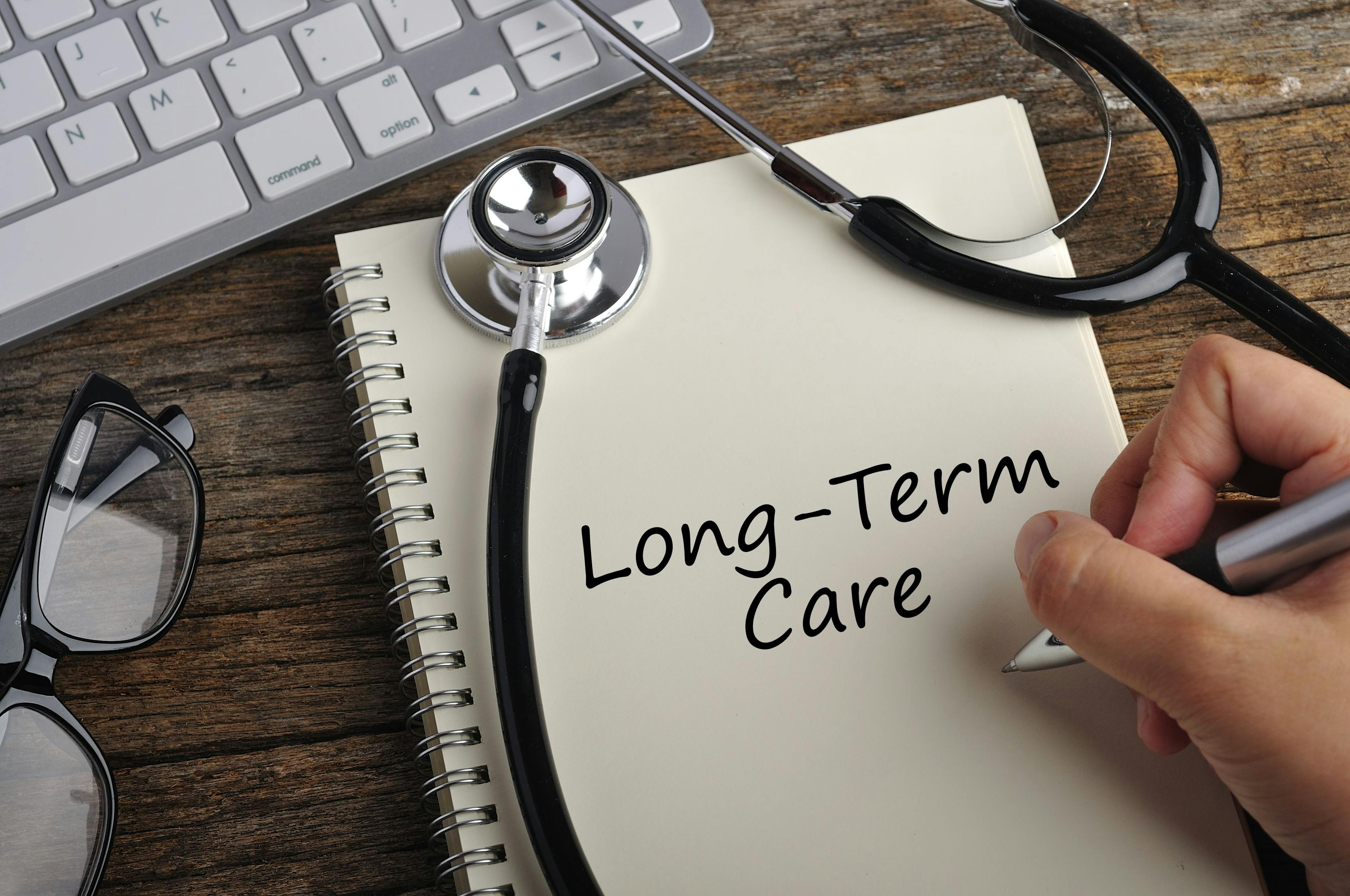 Women Hand Writes "long-term care" On Note Book